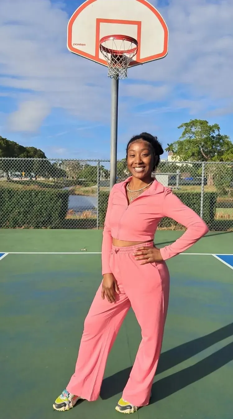 Janelle in a pink tracksuit on a sunny West Palm Beach basketball court